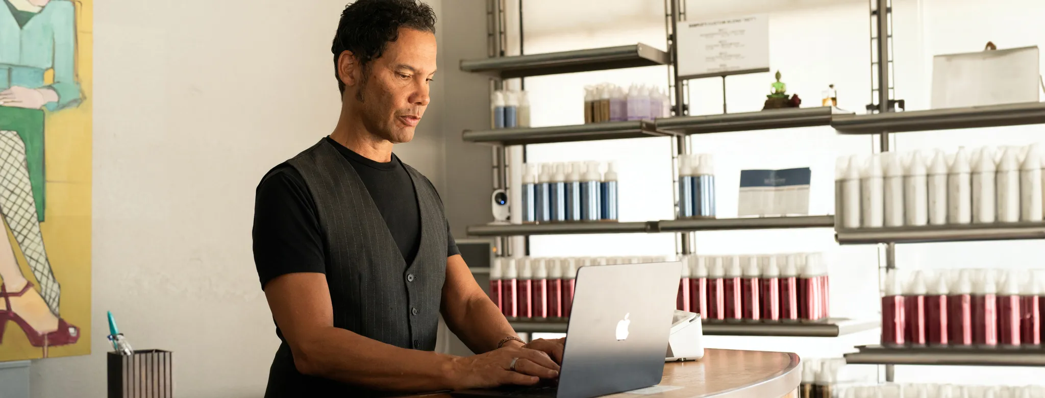 Spa business owner behind front desk working on laptop