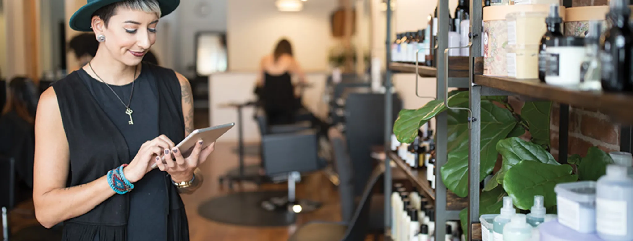woman with hat on ipad in salon with products