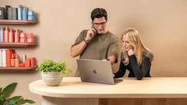 Two people working the front desk and using the computer 