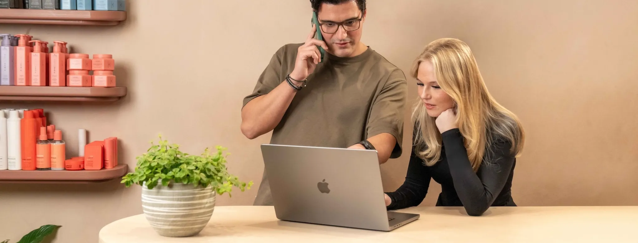 Two people working the front desk and using the computer 